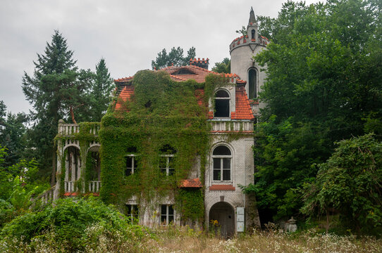Abandoned overgrown mansion with spiral staircase, old car and ruined interior