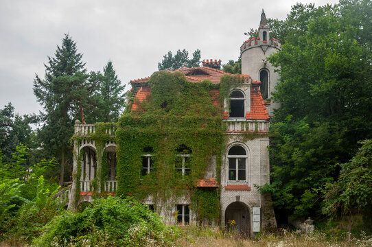 Abandoned overgrown mansion with spiral staircase, old car and ruined interior