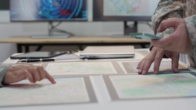 Military officers analyzing tactical map documents and digital tablet in command war room