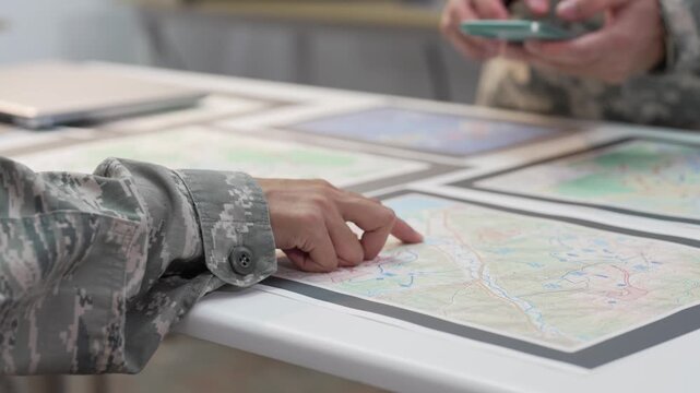 Military officers analyzing tactical map documents and digital tablet in command war room
