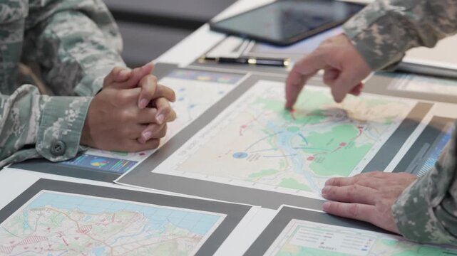 Military officers analyzing tactical map documents and digital tablet in command war room