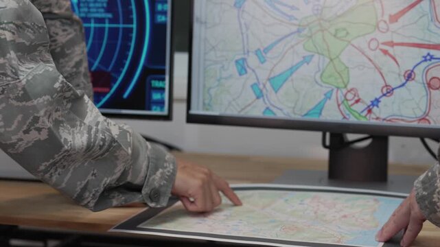 Military officers analyzing tactical map documents and digital tablet in command war room