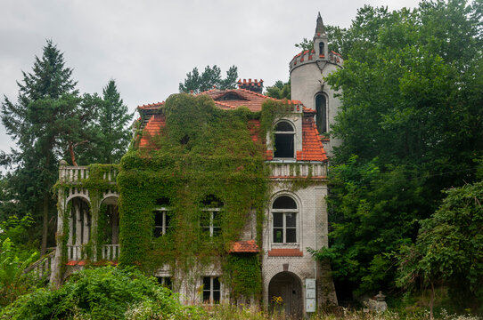 Abandoned overgrown mansion with spiral staircase, old car and ruined interior
