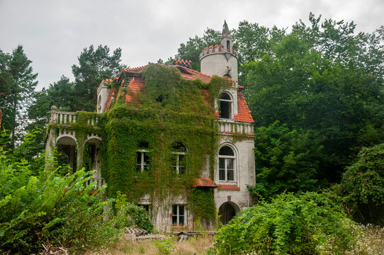 Abandoned overgrown mansion with spiral staircase, old car and ruined interior