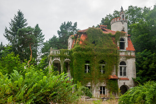 Abandoned overgrown mansion with spiral staircase, old car and ruined interior