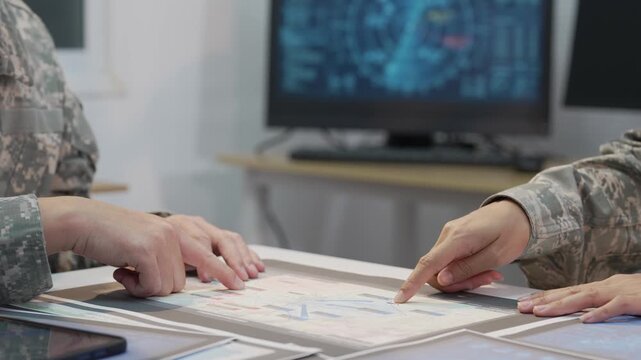 Military officers analyzing tactical map documents and digital tablet in command war room