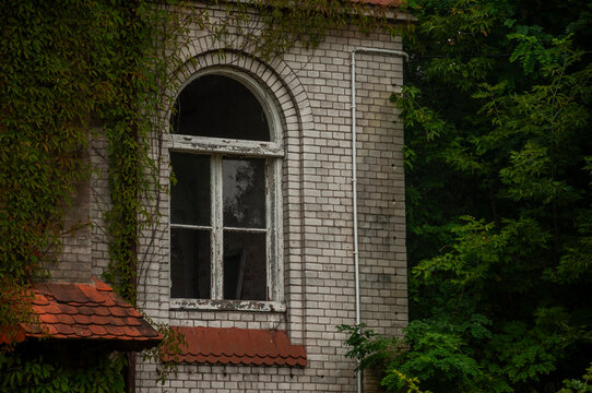 Abandoned overgrown mansion with spiral staircase, old car and ruined interior