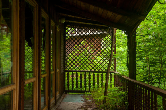 Abandoned overgrown mansion with spiral staircase, old car and ruined interior