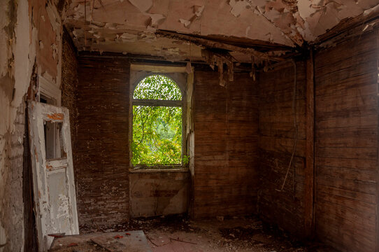 Abandoned overgrown mansion with spiral staircase, old car and ruined interior