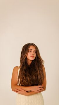 Young woman with long, wavy brown hair looking away thoughtfully