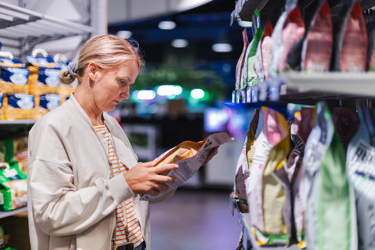 Woman Reading Packaged Pet Food Label in Store