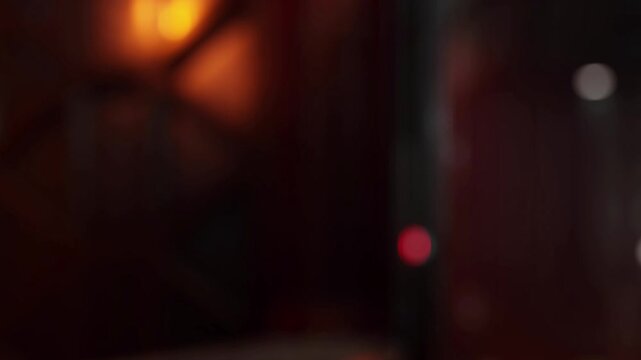A warm light shines in a dimly lit room. The colors mix in a way that forms shadows and different shapes. The scene looks active with hints of movement in the background.
