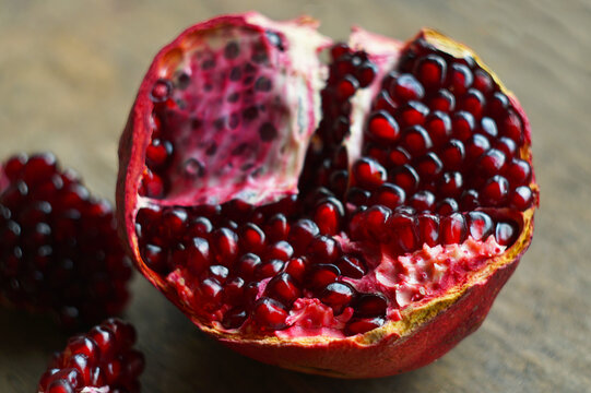 Close up of a cracked open ripe pomegranate with fresh ruby red seeds.