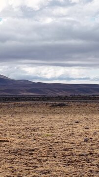 Car driving on a remote road through the vast arid landscape of Patagonia, Argentina