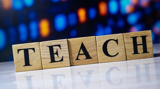 Teach word spelled with wooden blocks on reflective table for educational development and mentorship concepts.