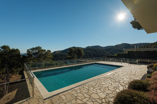 Modern outdoor swimming pool with stone deck and mountain view under clear blue sky