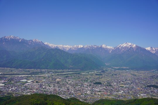 北アルプス　鷹狩山から望む残雪の北アルプスと新緑の大町市街	