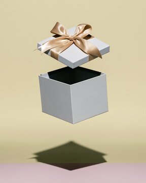 Open gift box with a floating lid and satin bow, featuring soft pastel tones and clean edges for product launch teasers and surprise promotions