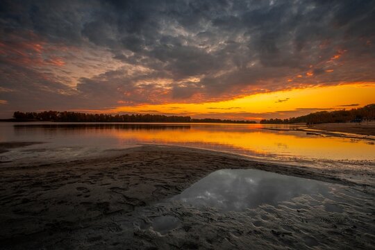 Warm orange sunset over a river with sandbars in the foreground