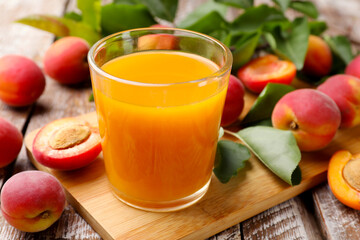 Apricot juice in glass, fresh fruits and leaves on wooden table, closeup © New Africa