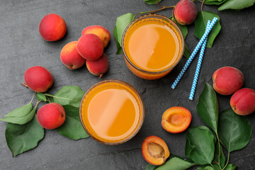 Apricot juice in glasses, fresh fruits and drinking straws on black table, flat lay © New Africa