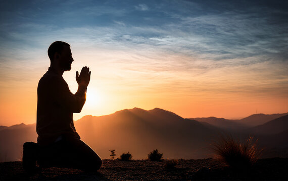 Prayer. Repentance. A man on his knees. Silhouette of a man on a blue sky background. Kneeling Prayer to God. Glorification. Praising God. Christian. Zeal for God
