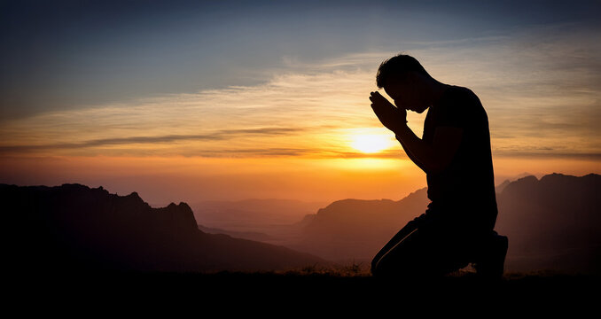 Prayer. Repentance. A man on his knees. Silhouette of a man on a blue sky background. Kneeling Prayer to God. Glorification. Praising God. Christian. Zeal for God