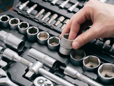 Mechanic hand taking out a metal socket head from a professional tool box organizer close up.	
