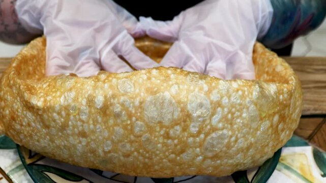 A person holding a loaf of bread in white gloves, a symbol of care and precision