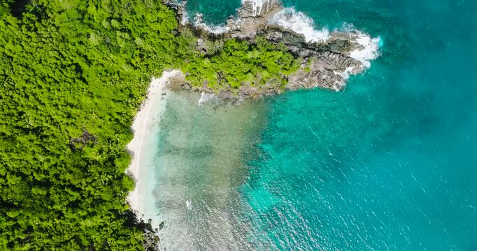 Turquoise coastline with rocky outcrops extending into the ocean, bordered by dense forest and greenery. Seychelles, Mahe.
