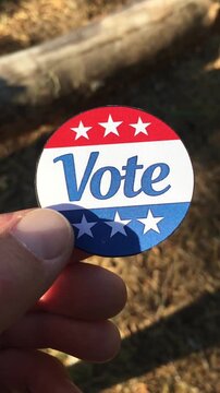 Hand holding Vote sticker on rural ground background, concept of US midterms and farming policy
