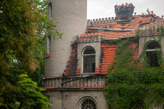 Abandoned overgrown mansion with spiral staircase, old car and ruined interior