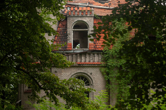 Abandoned overgrown mansion with spiral staircase, old car and ruined interior