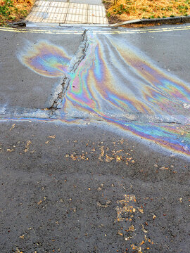 A leaked Car Oil Petrol in The Rain on a Tarmac Road Metallic Rainbow Gasoline