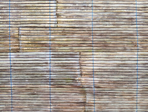 Rustic bamboo mat texture with thin wooden strips and blue woven thread accents bamboo surface parallel lines