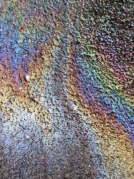A leaked Car Oil Petrol in The Rain on a Tarmac Road Metallic Rainbow Gasoline