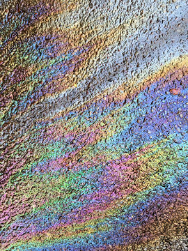 A leaked Car Oil Petrol in The Rain on a Tarmac Road Metallic Rainbow Gasoline