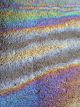 A leaked Car Oil Petrol in The Rain on a Tarmac Road Metallic Rainbow Gasoline