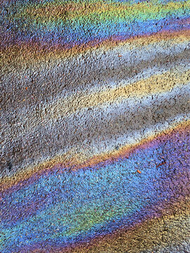 A leaked Car Oil Petrol in The Rain on a Tarmac Road Metallic Rainbow Gasoline