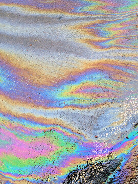 A leaked Car Oil Petrol in The Rain on a Tarmac Road Metallic Rainbow Gasoline