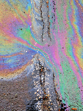 A leaked Car Oil Petrol in The Rain on a Tarmac Road Metallic Rainbow Gasoline