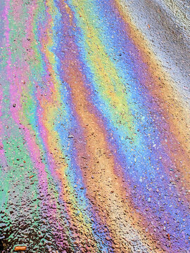 A leaked Car Oil Petrol in The Rain on a Tarmac Road Metallic Rainbow Gasoline