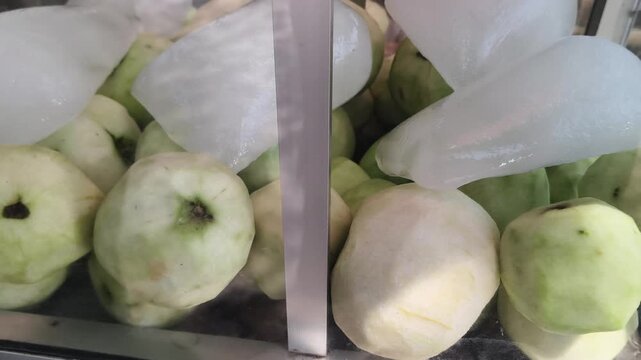 Close up of fresh green guavas wrapped in protective plastic at market
