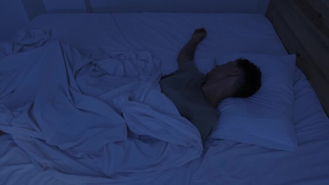 Sweating man suffering from night sweats and extreme heat, tossing in bed and throwing off covers on hot restless night