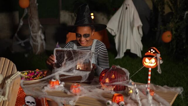 Little girl with halloween costume opens a mystery box at night