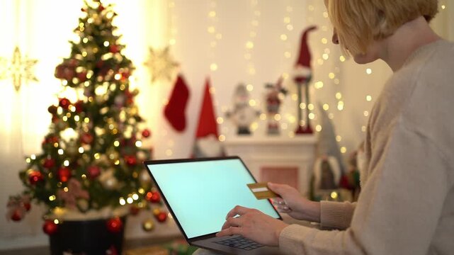 Woman buying christmas gifts online using her credit card and laptop