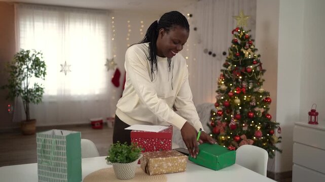 African woman writing a christmas card at home