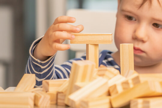 Toddler exploring shapes and balance with natural wooden blocks.