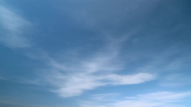 A still video frame displaying an overcast blue sky filled with soft, wispy cloud formations captured in a vertical.