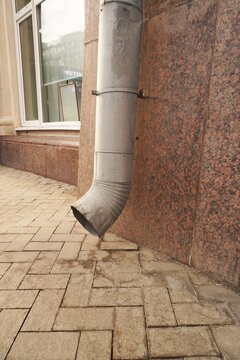 Close-up of the facade of a building with a drainpipe and a sidewalk, an urban architectural detail in an urban environment